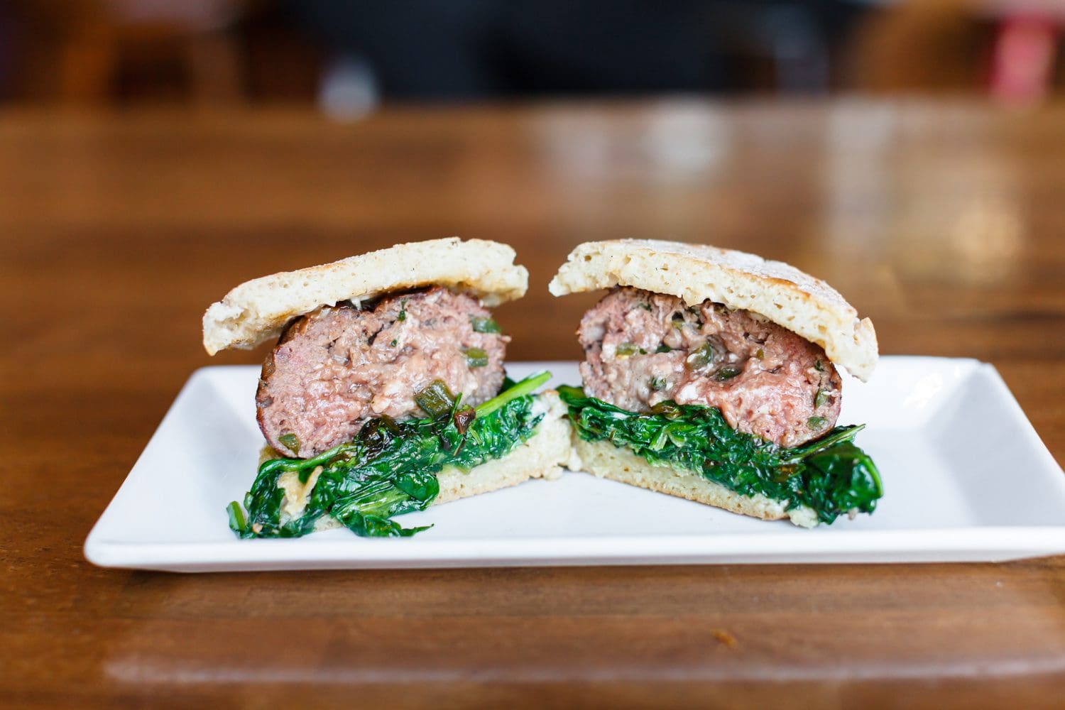 A sandwich with meat and spinach on white bread.