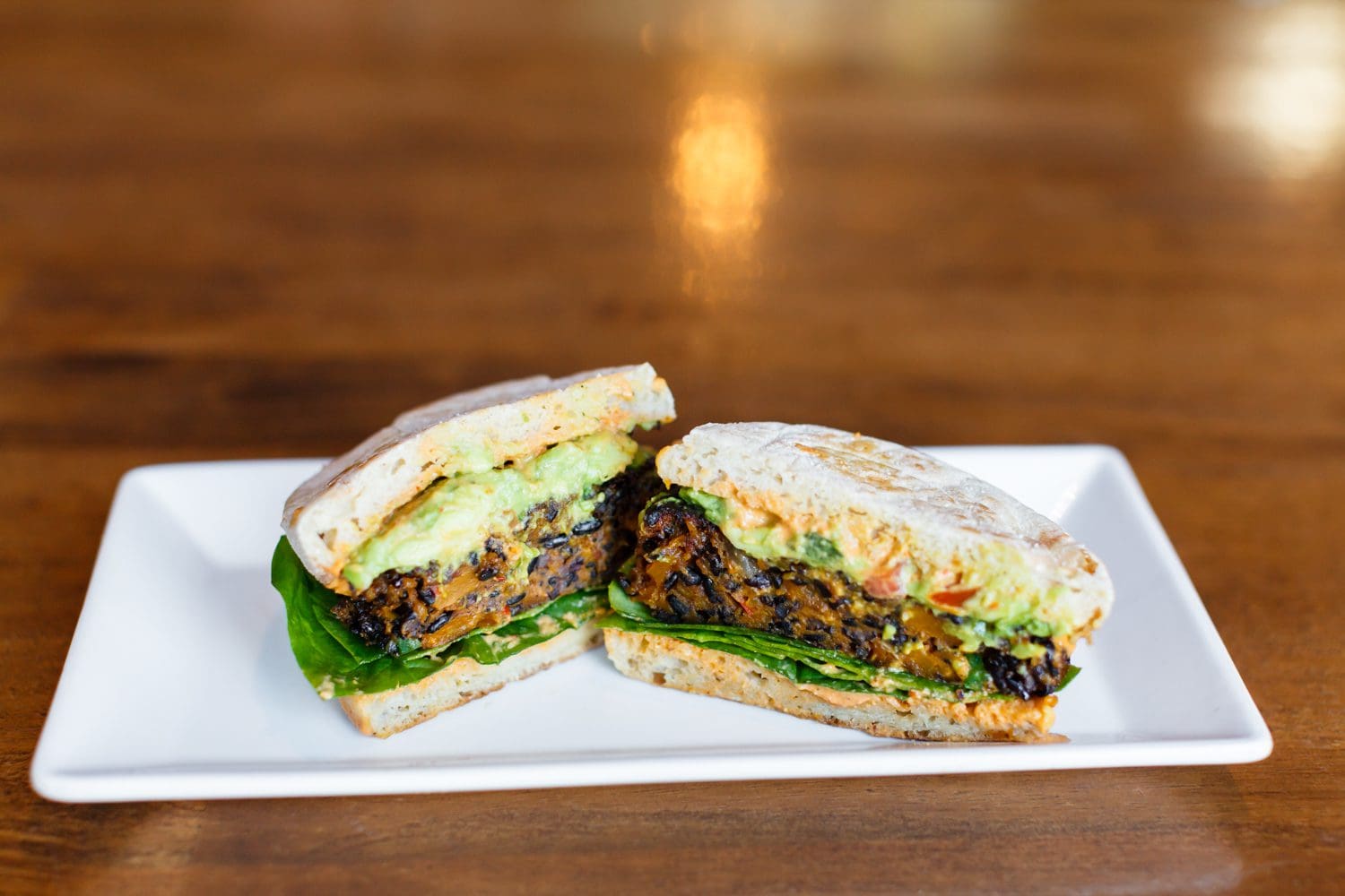 A veggie sandwich with lettuce on a white plate.